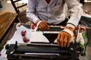 un uomo scrive su una macchian da scrivere con le mani coperte da bene e ferite
